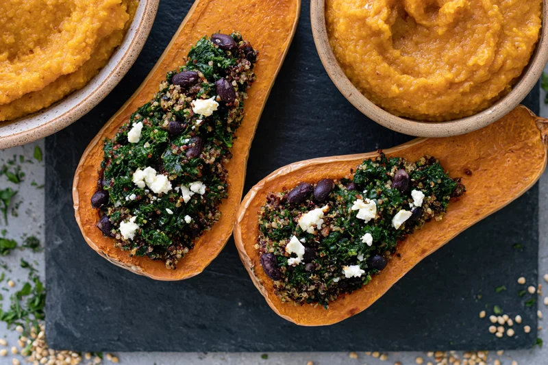 Roasted butternut squash halves stuffed with quinoa kale and black beans on slate plate