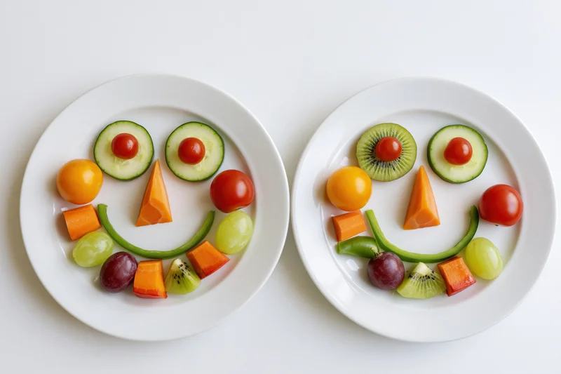 Two white plates with fruits arranged into smiling faces on a white surface