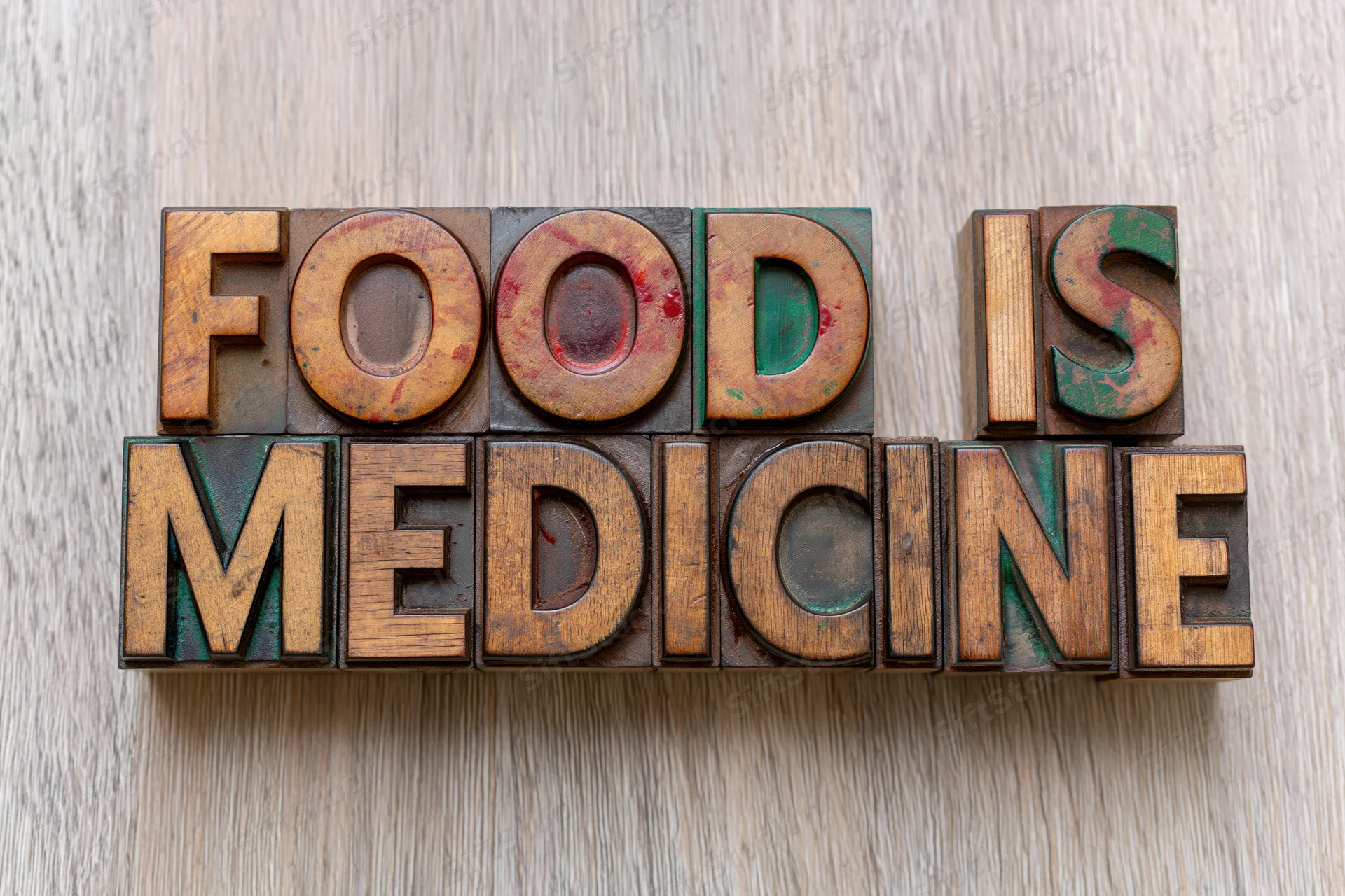 Vintage wooden letterpress blocks spelling food is medicine on a light wood surface