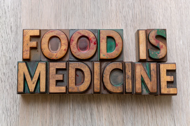 Vintage wooden letterpress blocks spelling food is medicine on a light wood surface