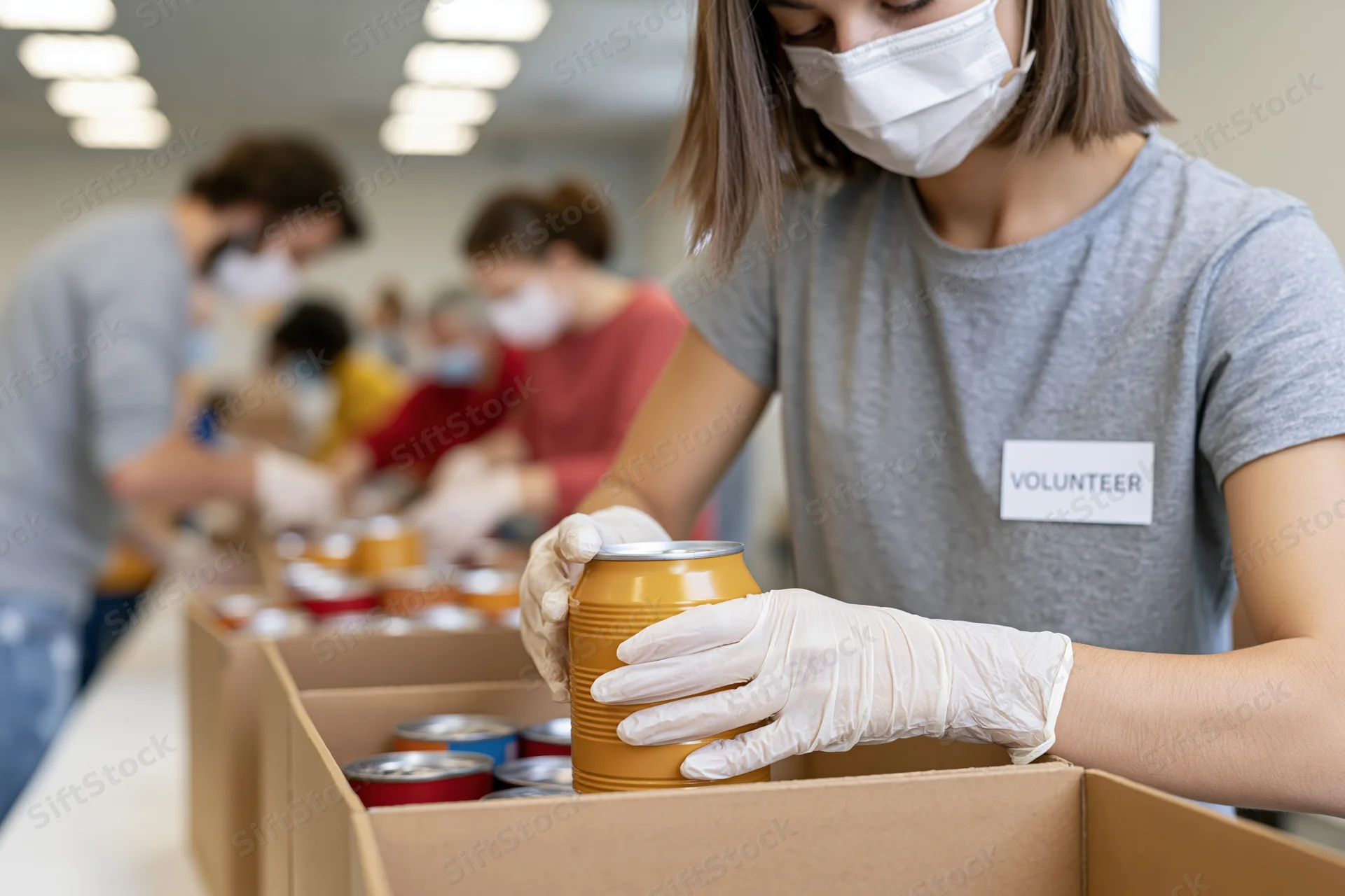 Volunteer placing canned food into a box at a donation center