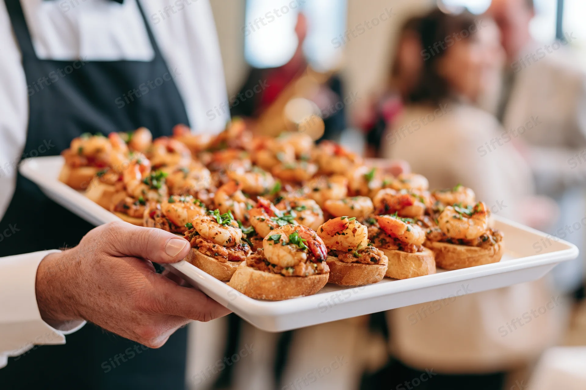 Waiter holding a tray of shrimp canapes at a restaurant event