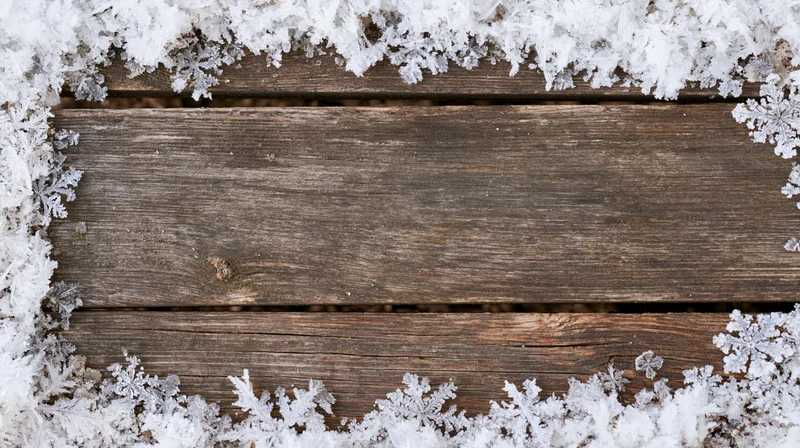 Weathered wooden planks bordered by snowflakes and frost, top view with central copyspace
