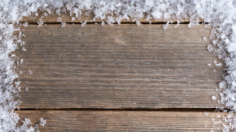Snow-covered weathered wooden planks with central copyspace