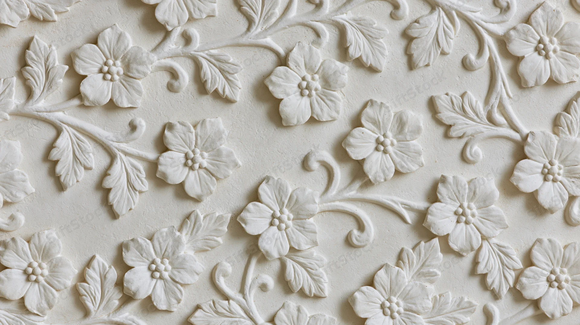 White plaster bas-relief panel with raised floral and leaf patterns covering the surface