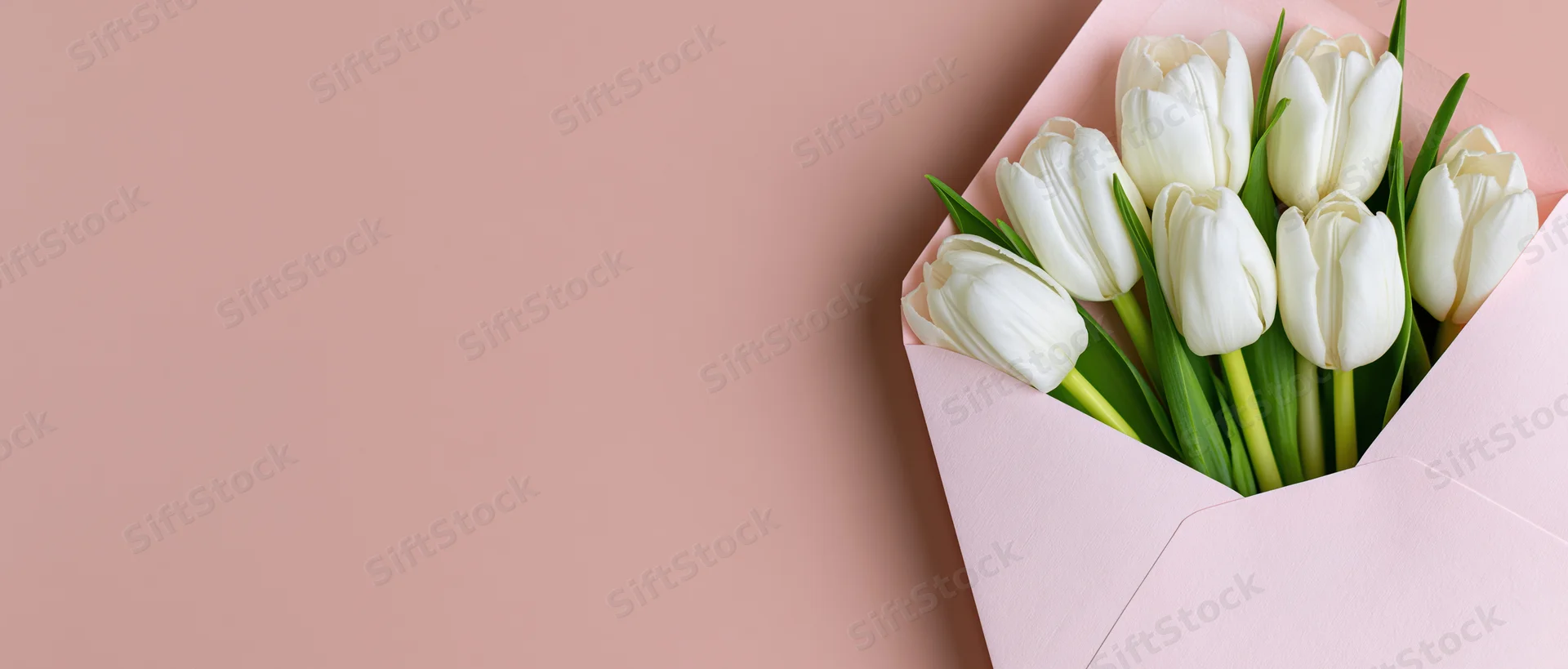 White tulips with green stems arranged in an open pink envelope on a pastel background