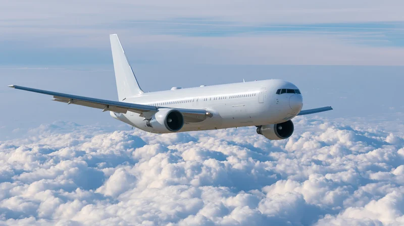 White commercial airliner flying above clouds in daytime sky