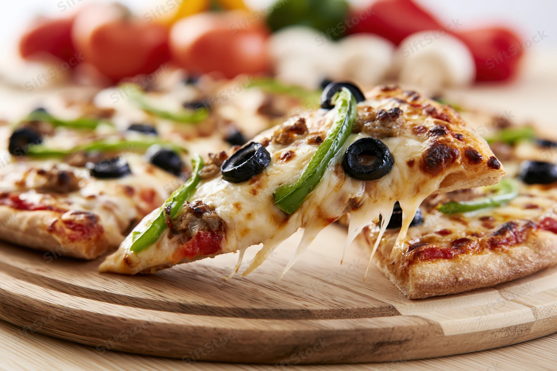Slice of pizza with melted cheese and toppings lifted from wooden board