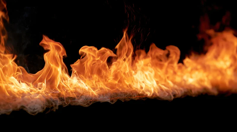 Horizontal band of fire burning against a pure black background