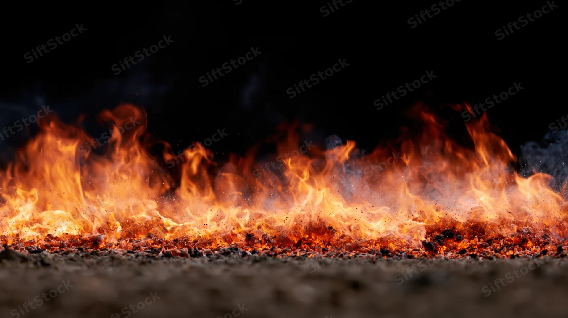 Low flames burning across a dark gravel surface at night