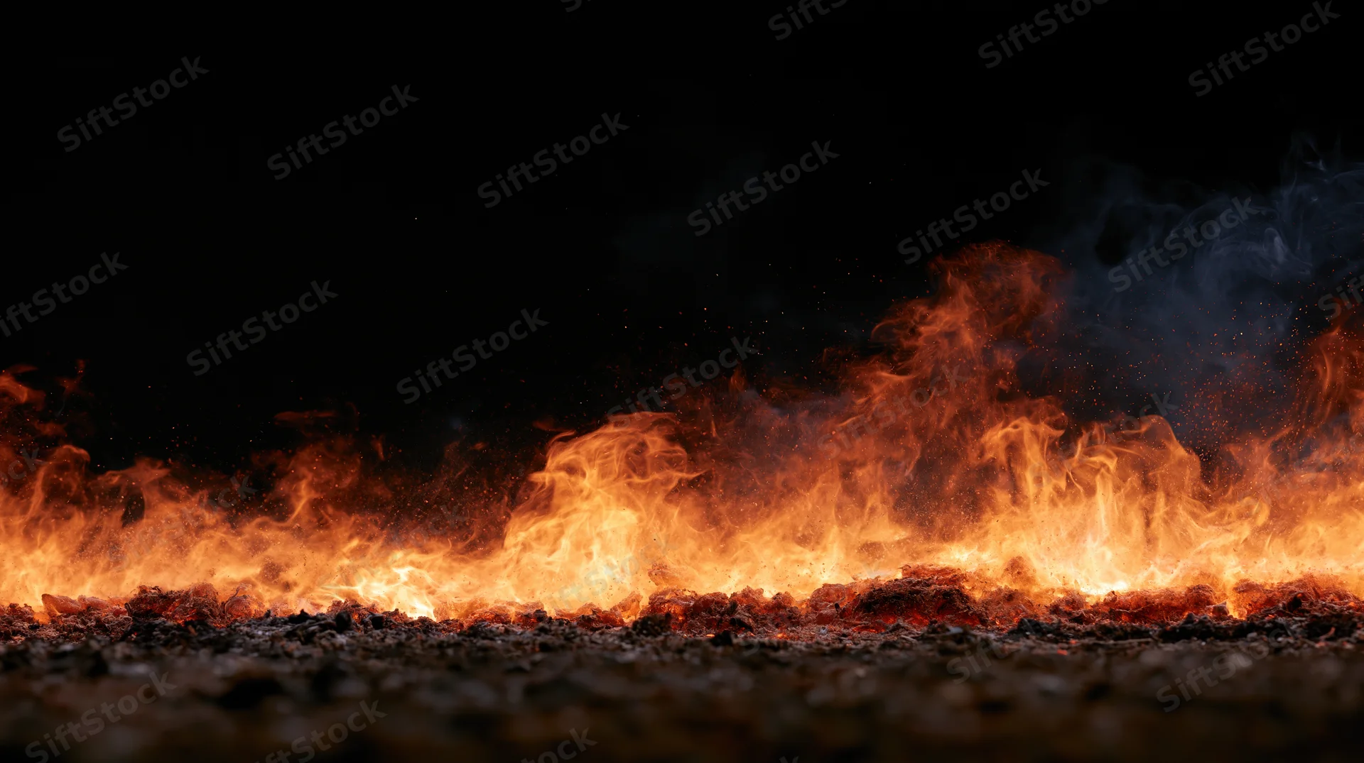 Low-burning fire spreading across gravel ground at night