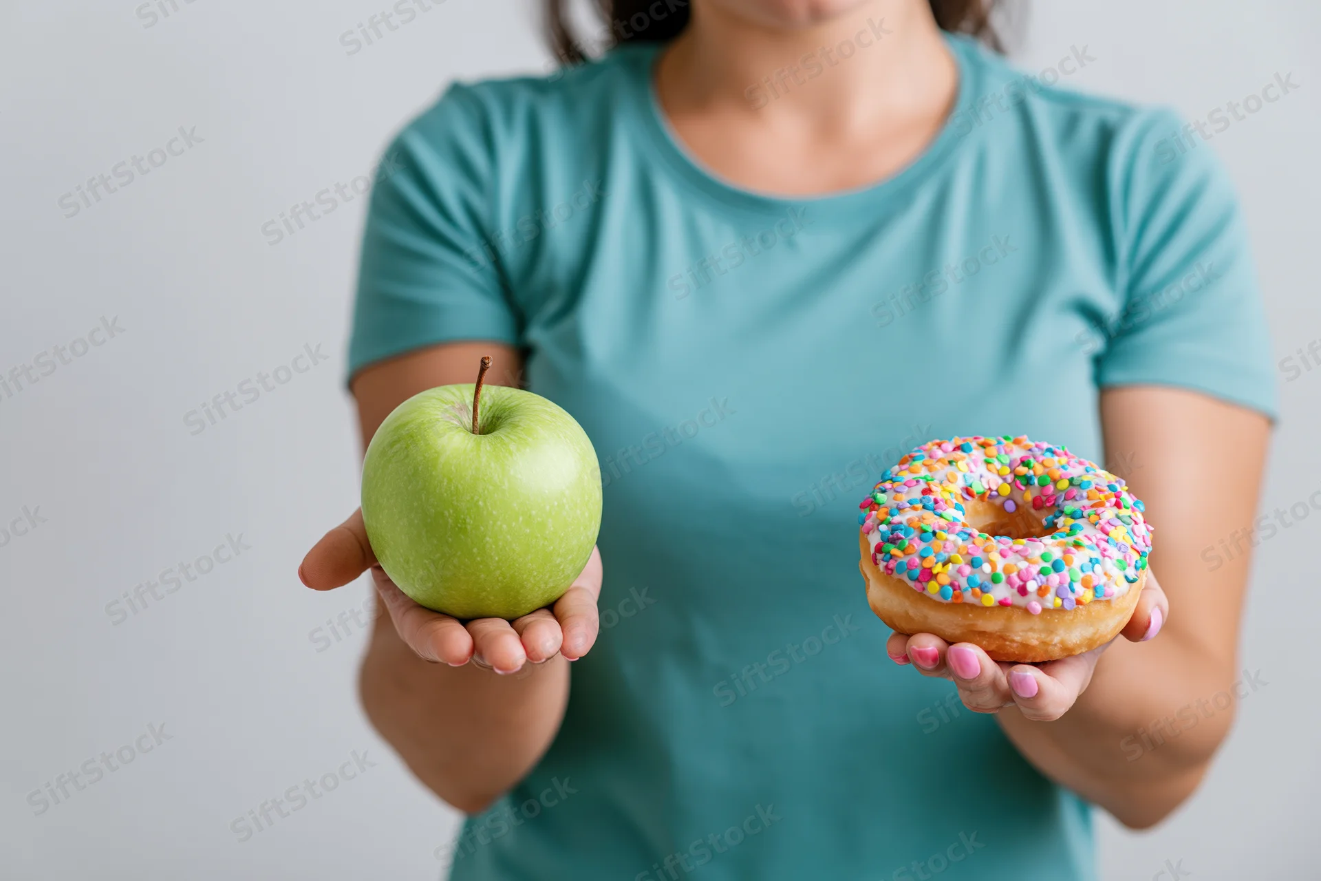 Woman holding a green apple and a rainbow-sprinkled donut in each hand against a white background