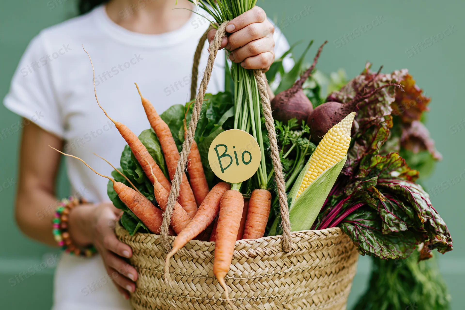 Woman holding a woven basket overflowing with fresh organic vegetables