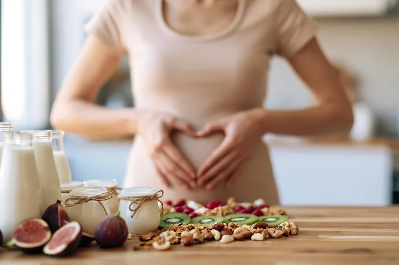 Woman making heart shape with hands over healthy foods on wooden table