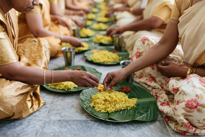 Women sharing a meal on banana leaves while sitting cross-legged on the floor
