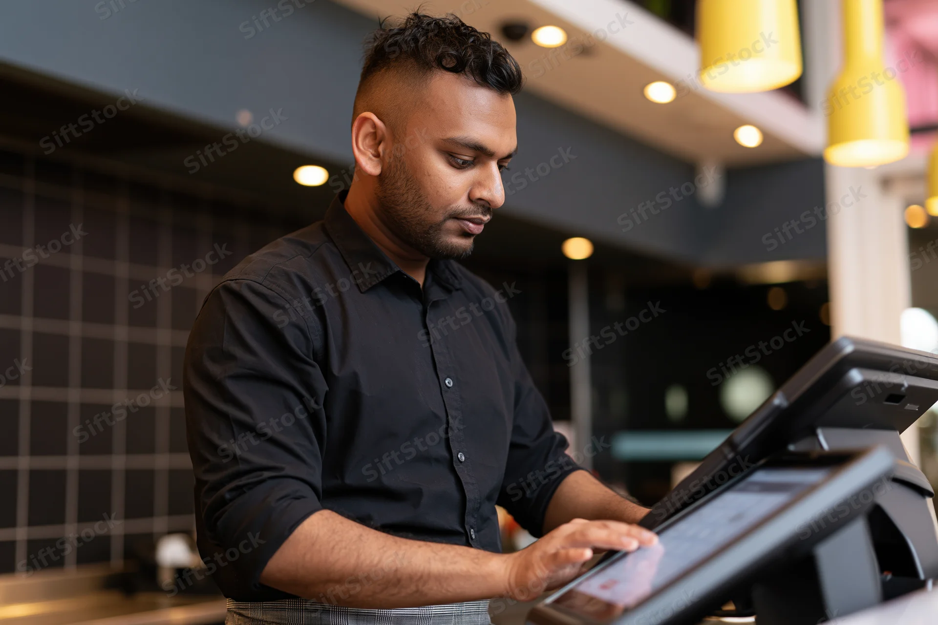 Man operating touchscreen cash register at cafe counter