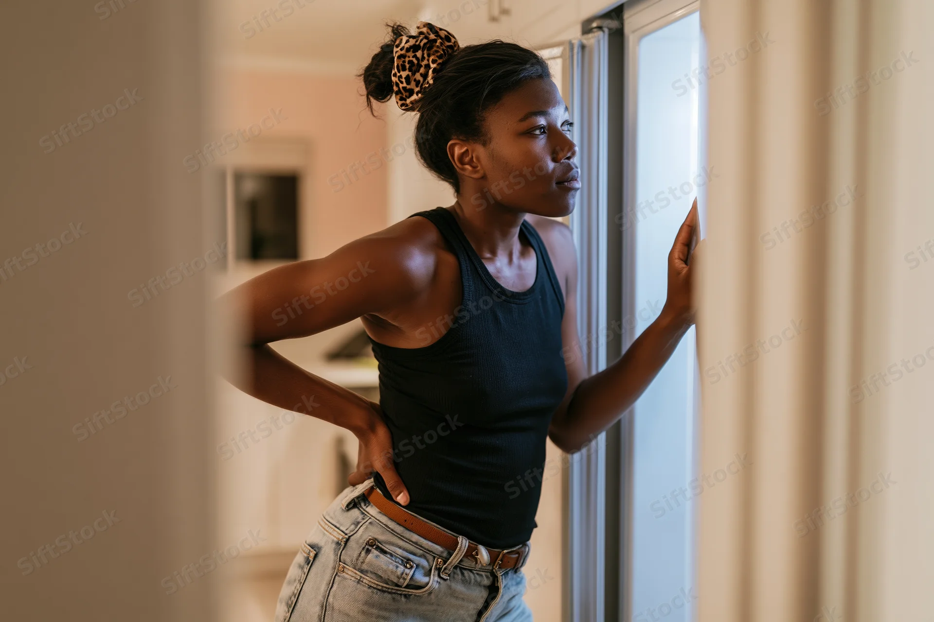 Young woman leaning into open refrigerator peering inside in kitchen