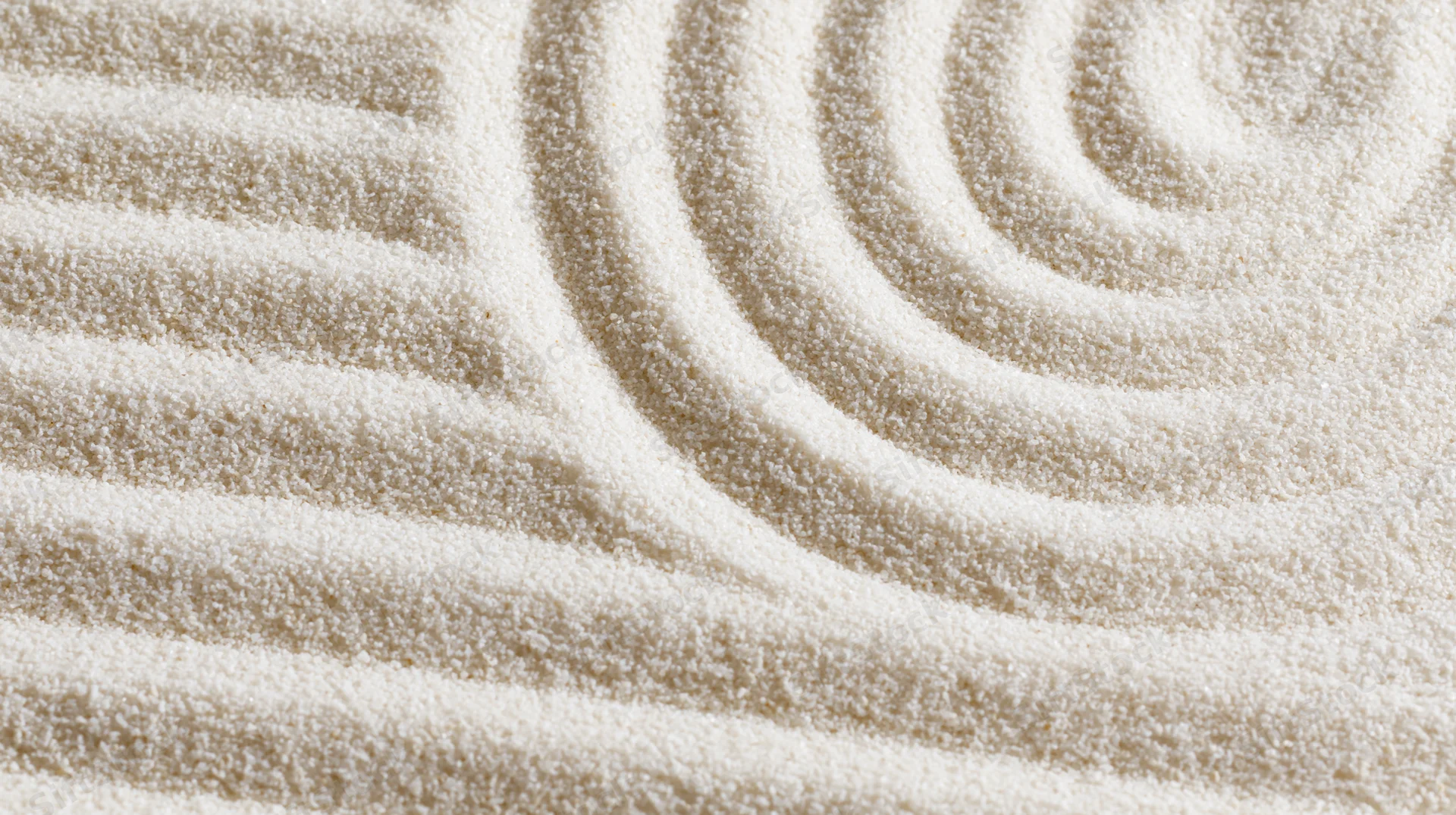 Raked sand in a zen garden forming parallel horizontal lines and a spiral pattern