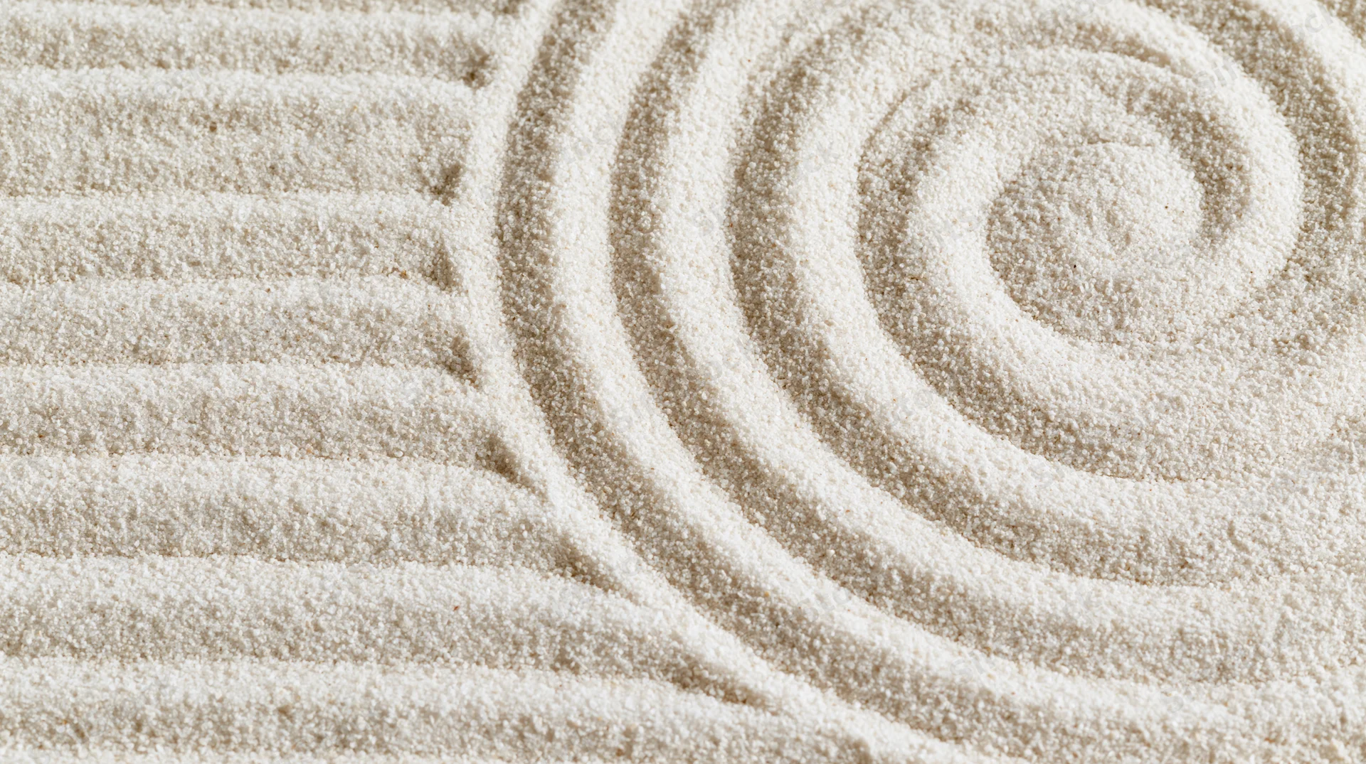 Raked sand in a zen garden forming parallel lines and a spiral pattern