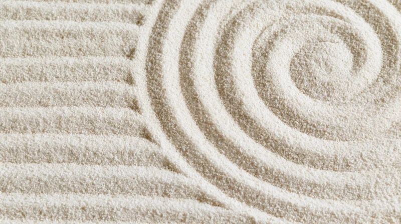Raked sand in a zen garden forming parallel lines and a spiral pattern