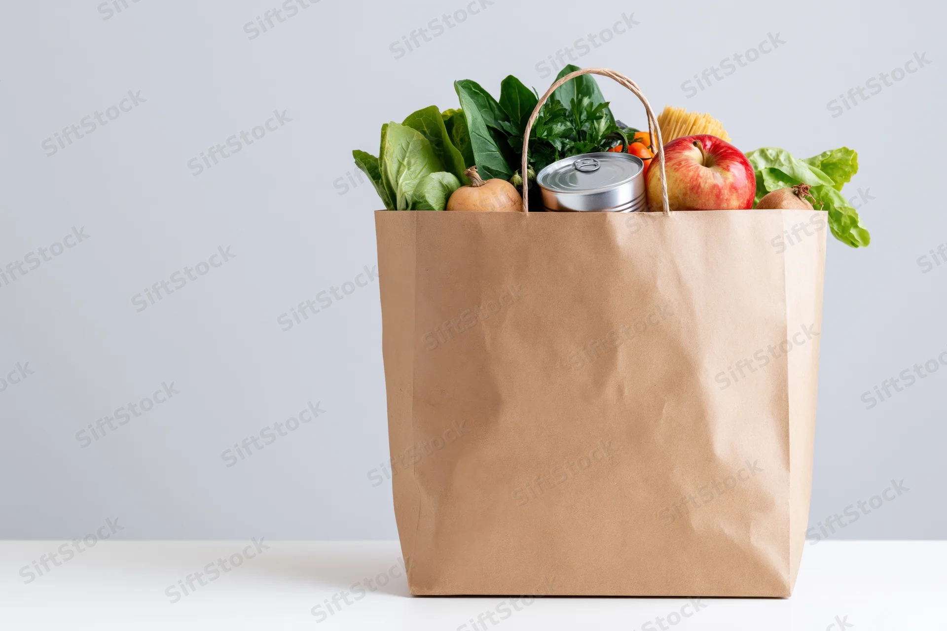 Kraft paper grocery bag filled with fresh vegetables and fruit on a white surface