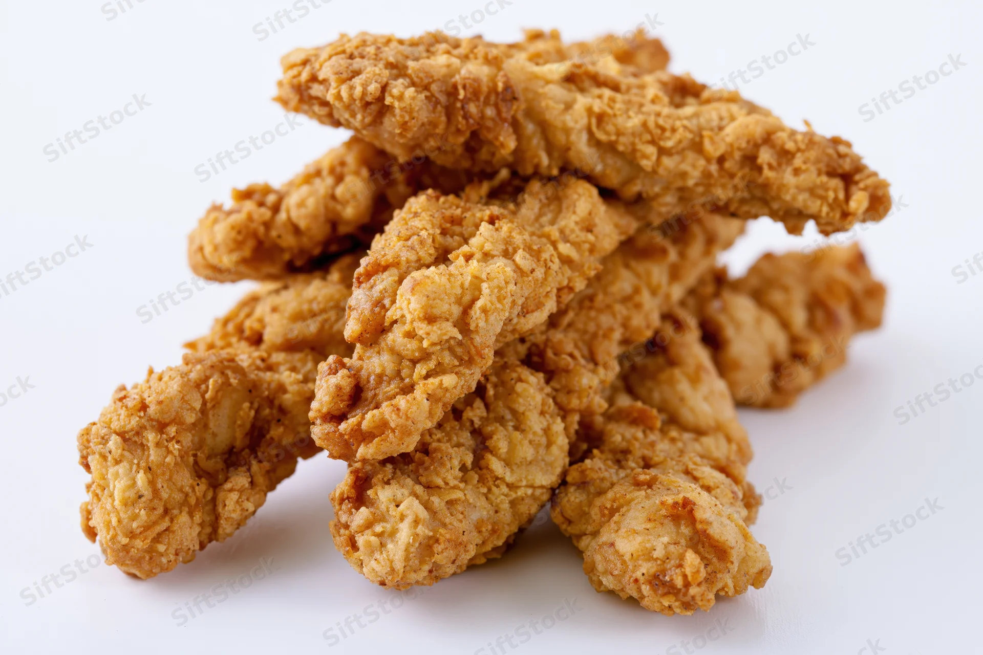 Crispy fried chicken tenders stacked loosely on a white surface