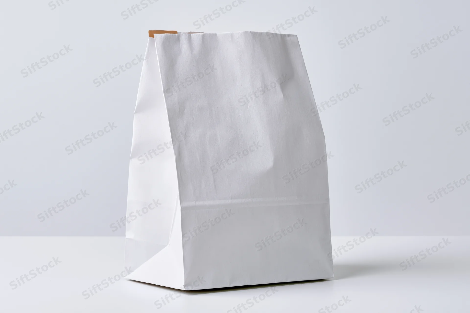 White paper bag standing upright on a flat surface with copyspace for branding or design