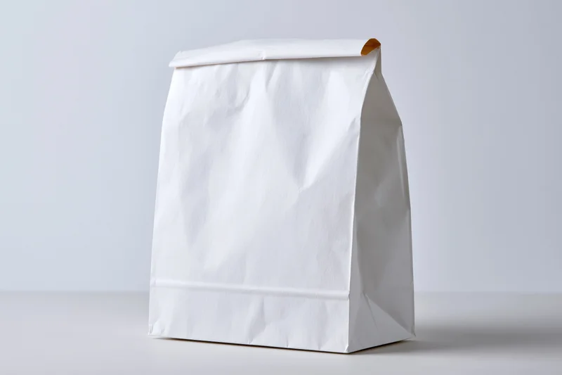 White paper bag standing upright on a flat surface with clean studio lighting