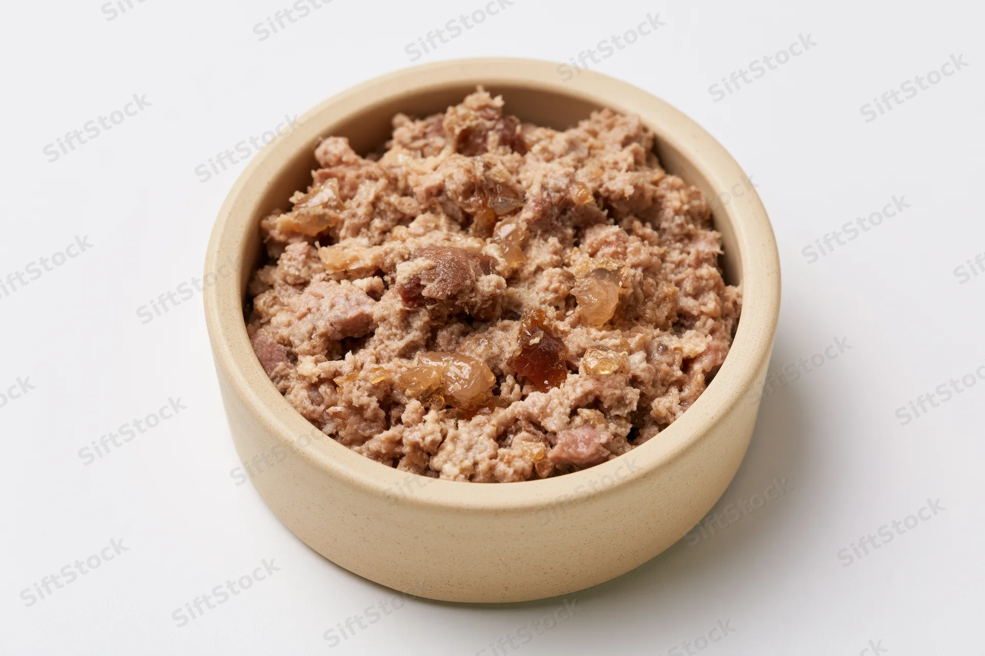 Chunky wet cat food in a small beige ceramic bowl on white background