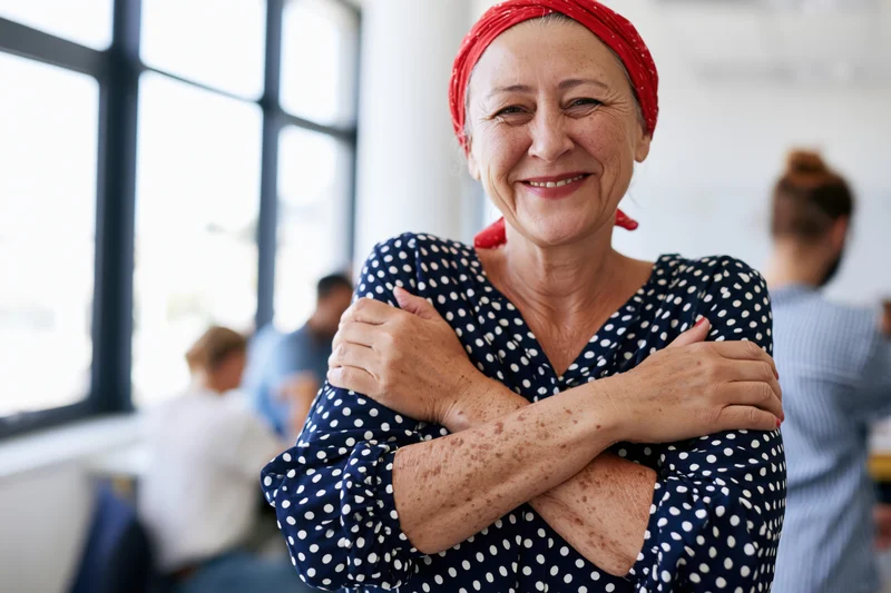 Smiling senior woman with arms crossed standing in office near window