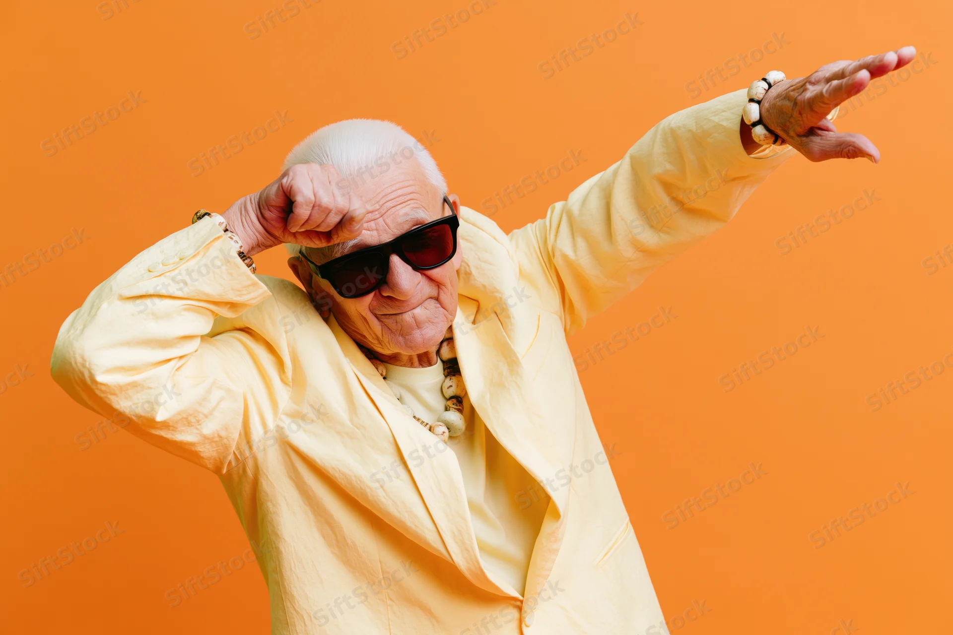 Senior man dancing in yellow jacket with sunglasses against orange background
