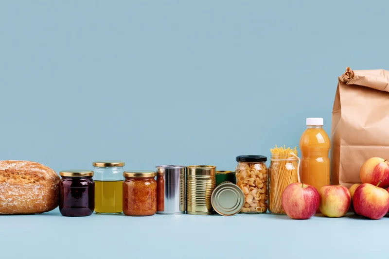 Assorted pantry staples and grocery items arranged in a row on a blue surface