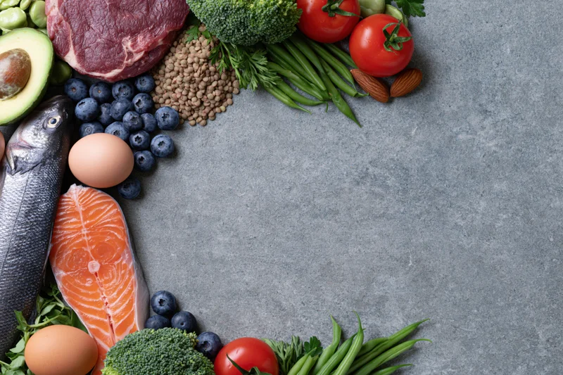 Assorted whole foods arranged in a circular frame on a gray stone surface