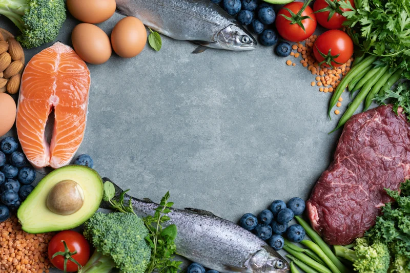 Assorted whole foods arranged in a circular frame on a slate surface with central copyspace