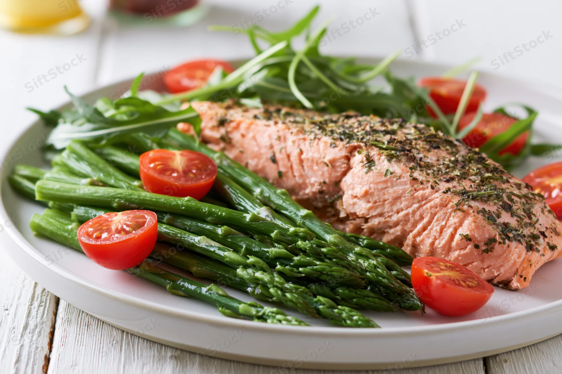 Baked salmon fillet with asparagus and cherry tomatoes on a white plate