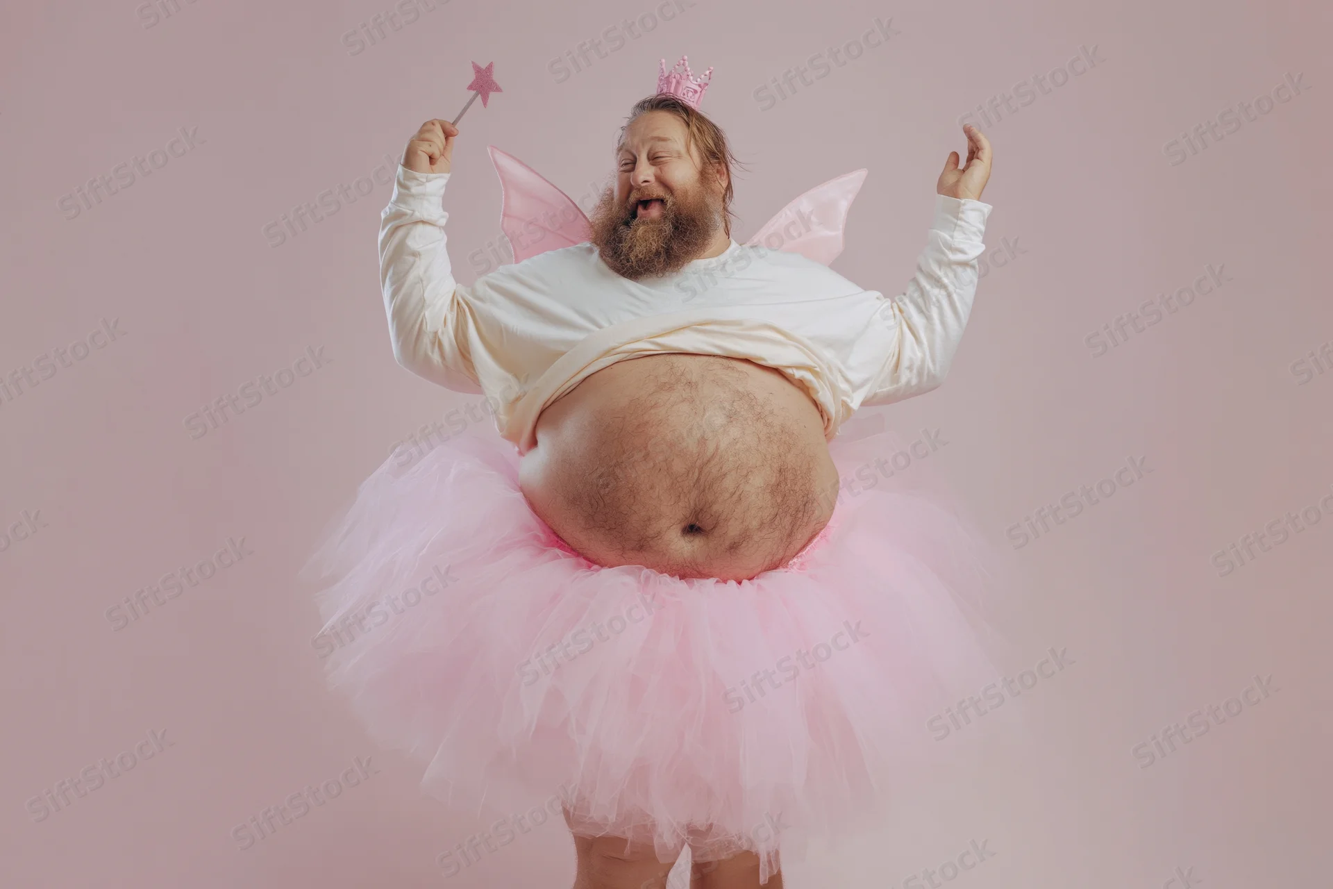 Bearded man in fairy costume with tutu and wand posing joyfully against pink background