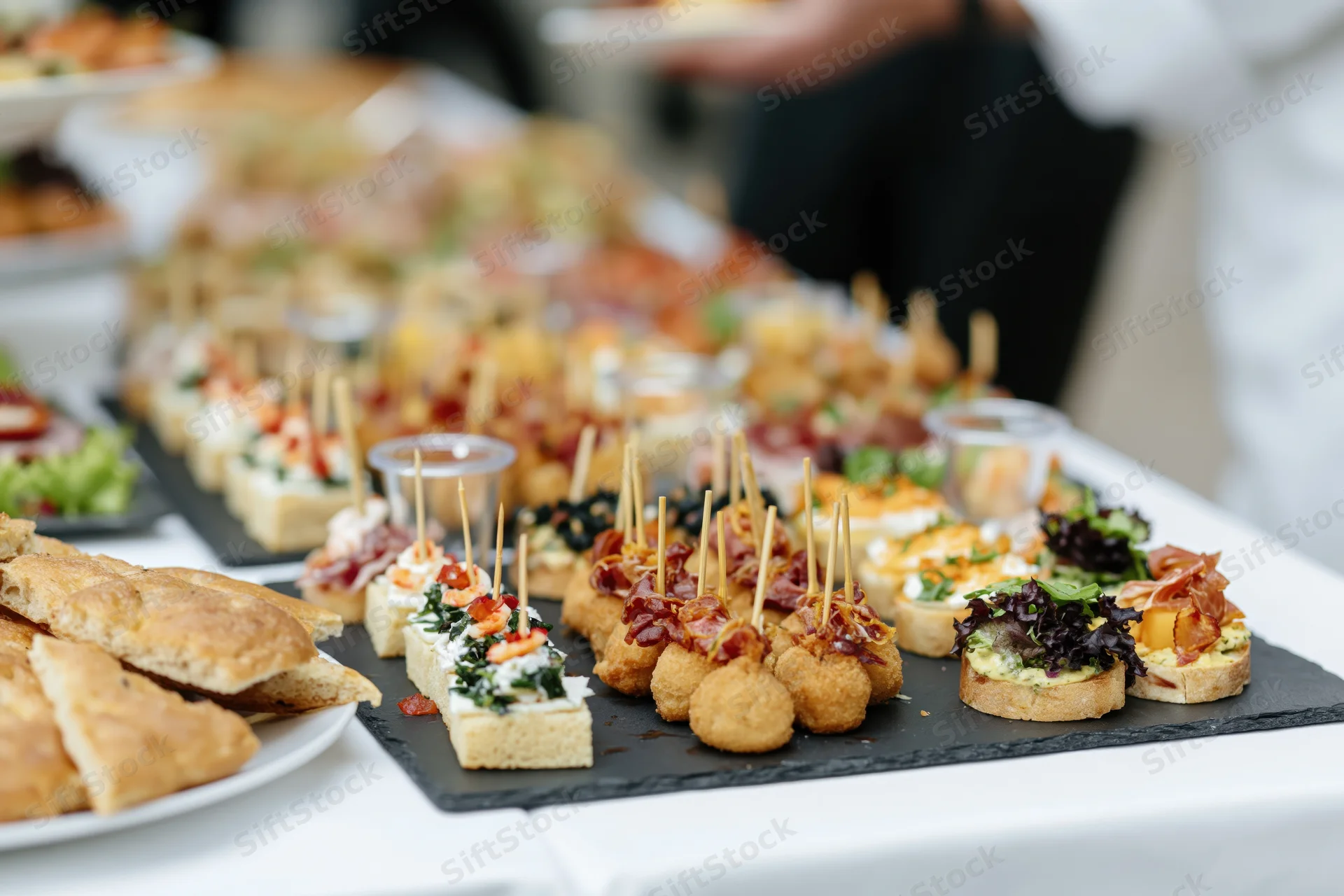 Assorted finger foods on slate platters arranged on a buffet table at an event