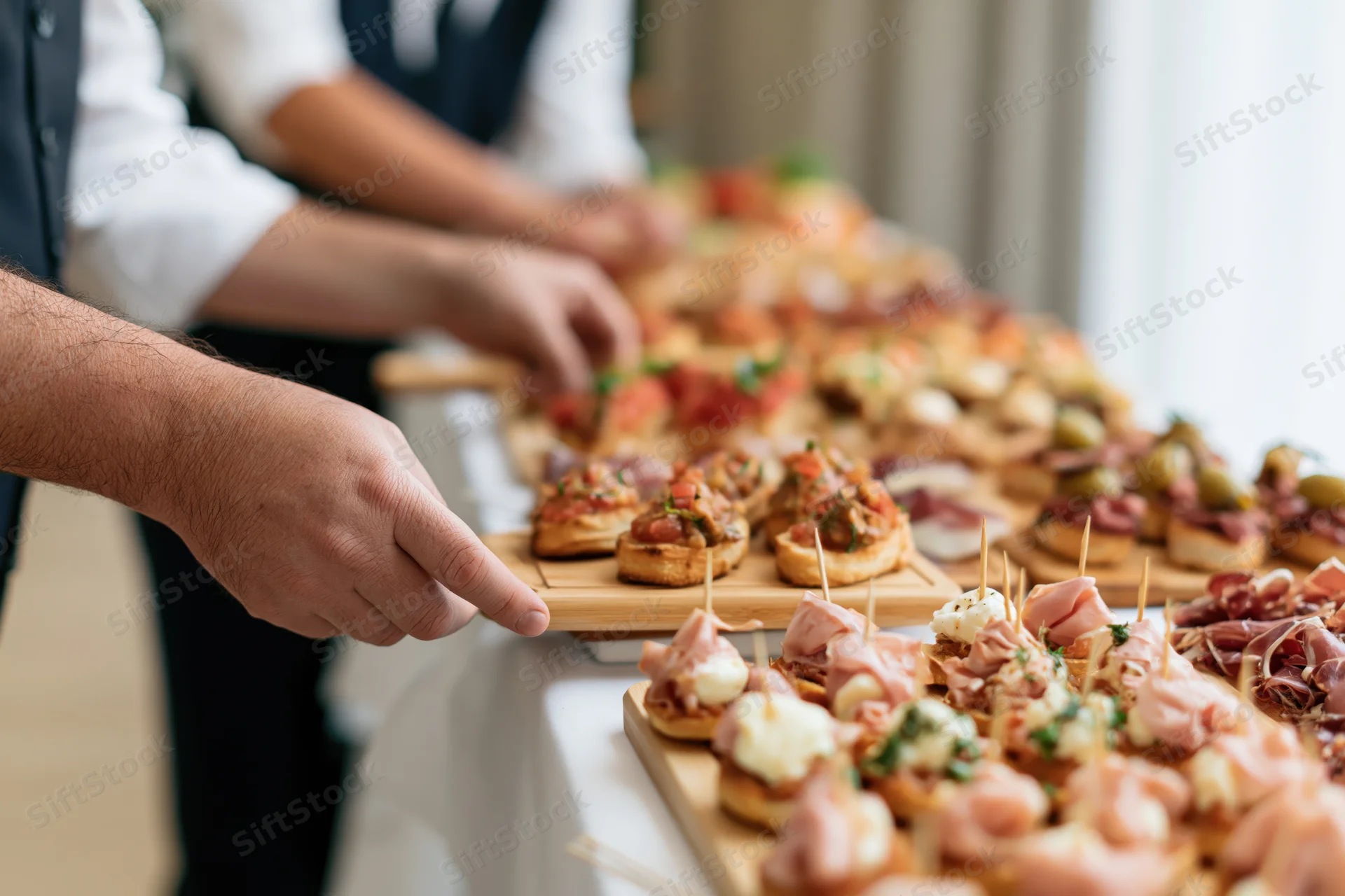 Catering staff arranging appetizers on wooden trays at a buffet table