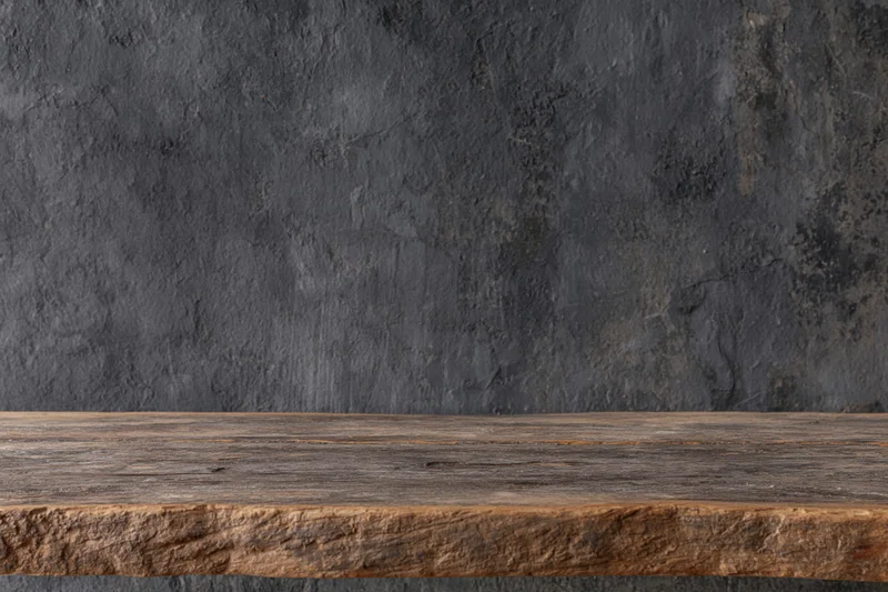 Weathered wooden shelf against dark textured concrete wall with copyspace above