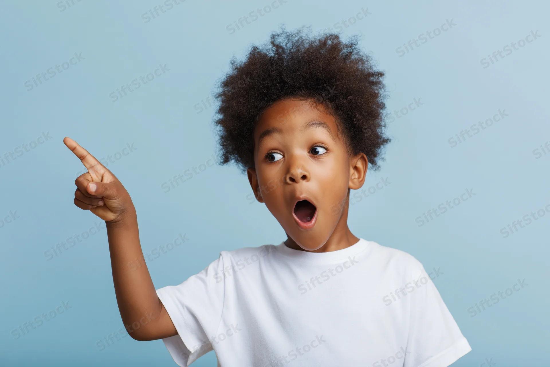 Young black boy with curly afro hair pointing upward with surprised expression against light blue background