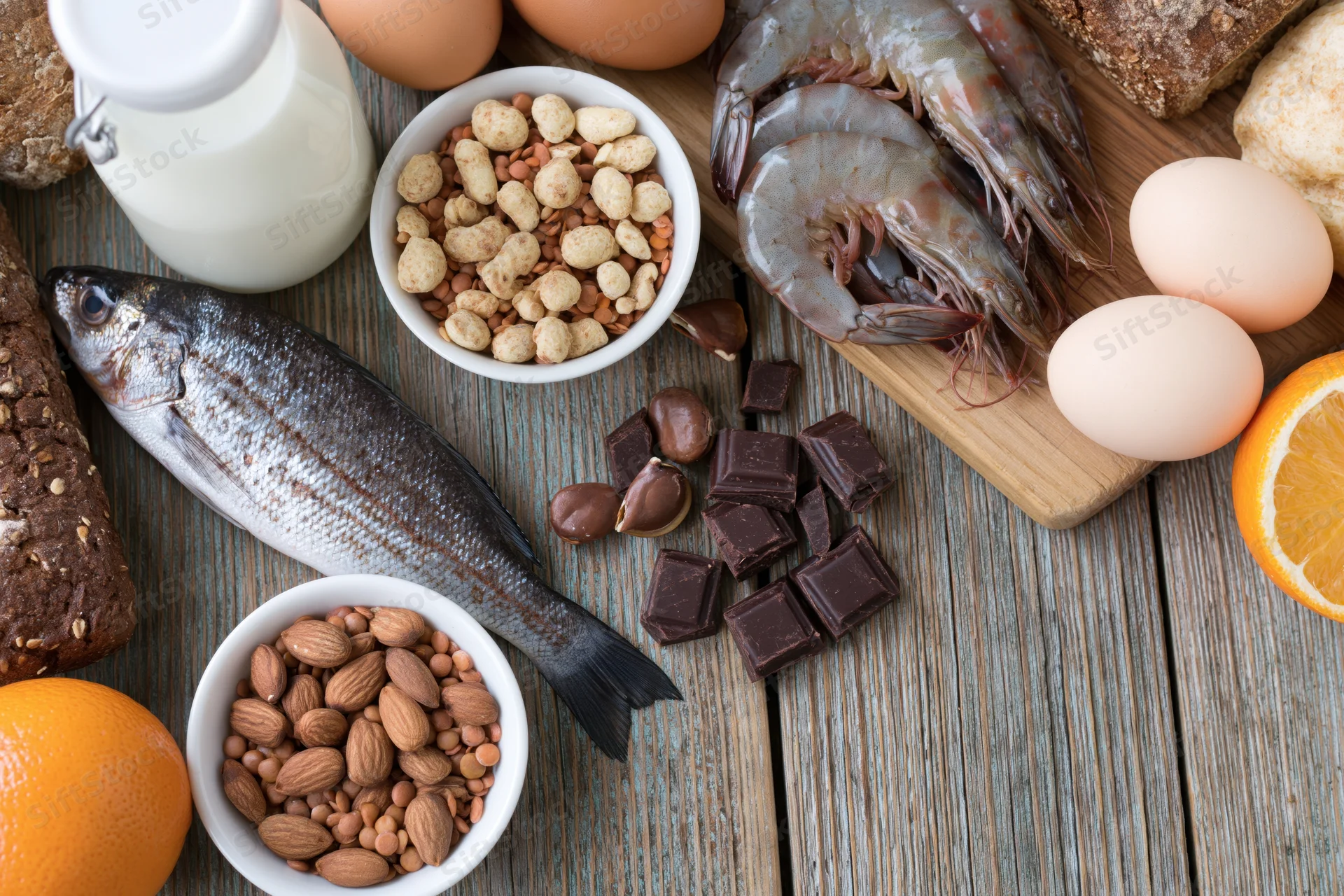 Various common food allergens arranged on a weathered wooden surface
