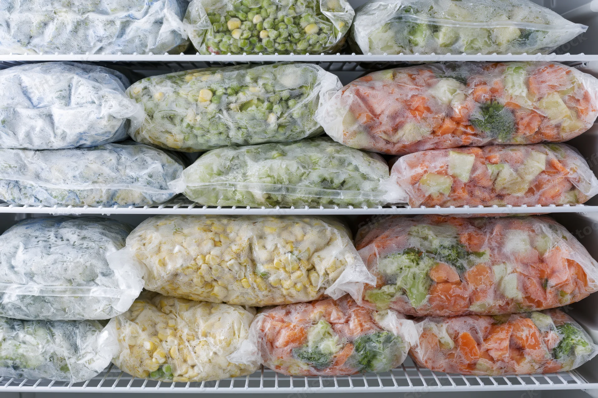 Frozen vegetables in clear plastic bags arranged on freezer shelves