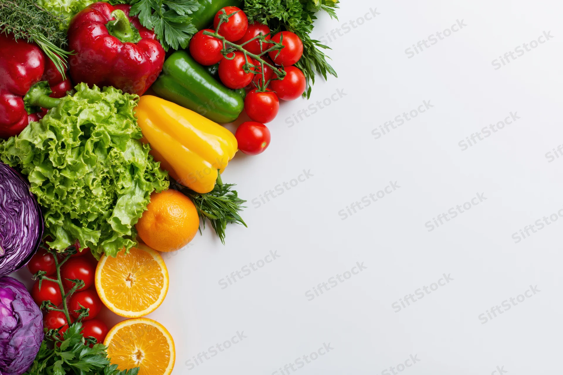 Fresh vegetables and fruits arranged along the left side on a white surface