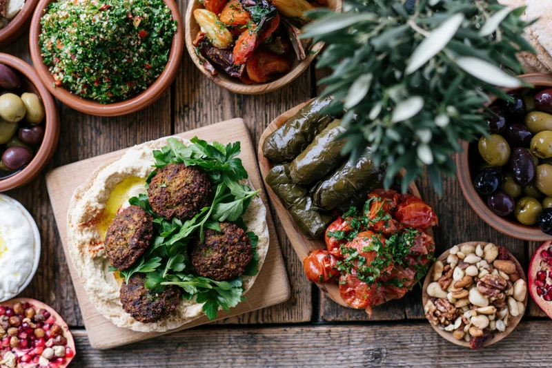 Middle eastern mezze spread with hummus, falafel, tabbouleh and olives on rustic wooden table