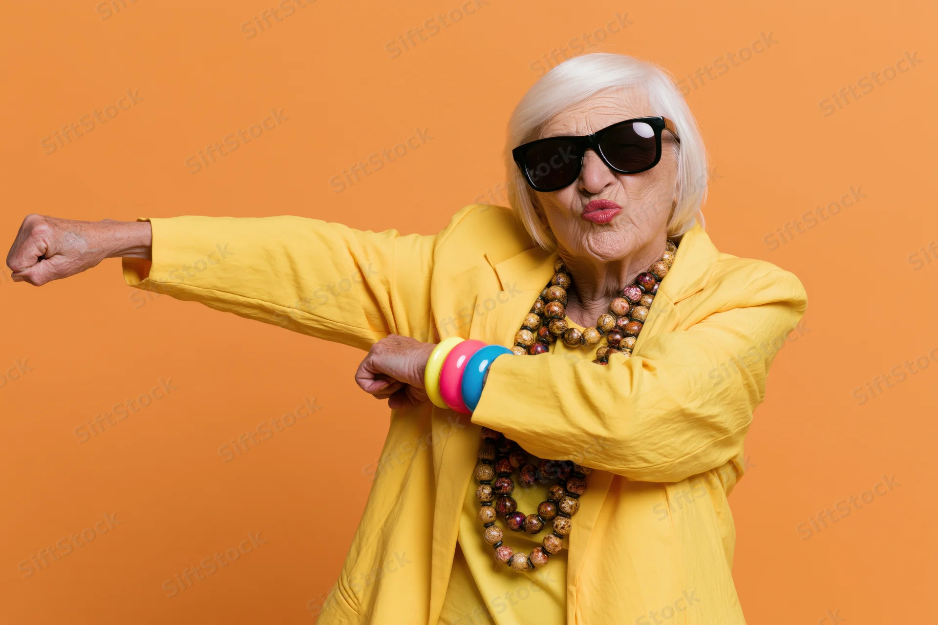 Senior woman dabbing in yellow jacket and sunglasses against orange background