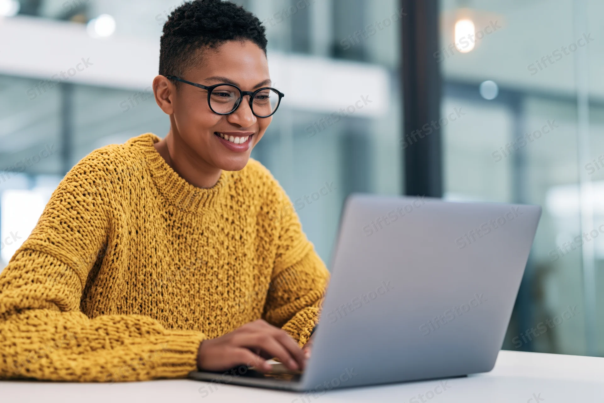 Woman smiling while typing on laptop at office desk