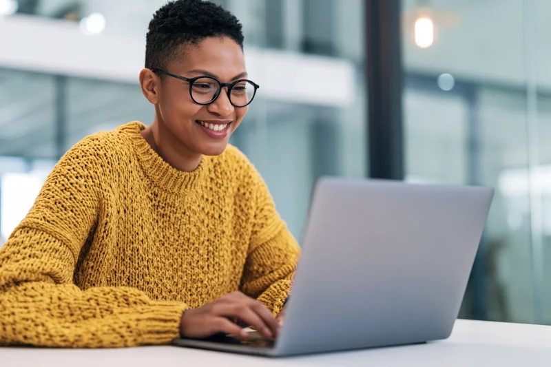 Woman smiling while typing on laptop at office desk