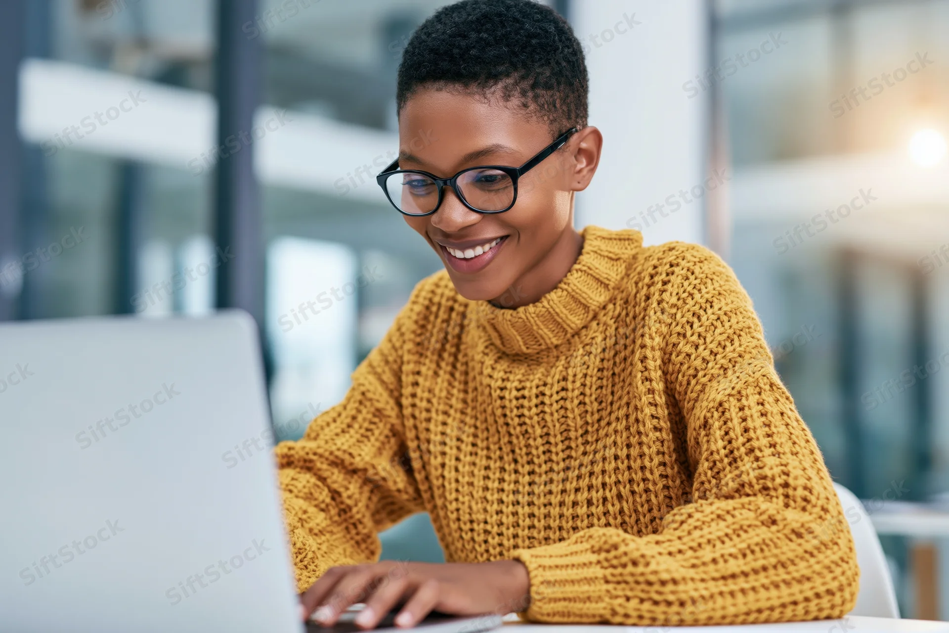 Woman smiling while working on laptop at office desk