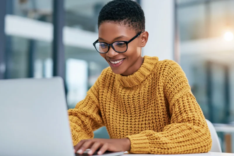 Woman smiling while working on laptop at office desk