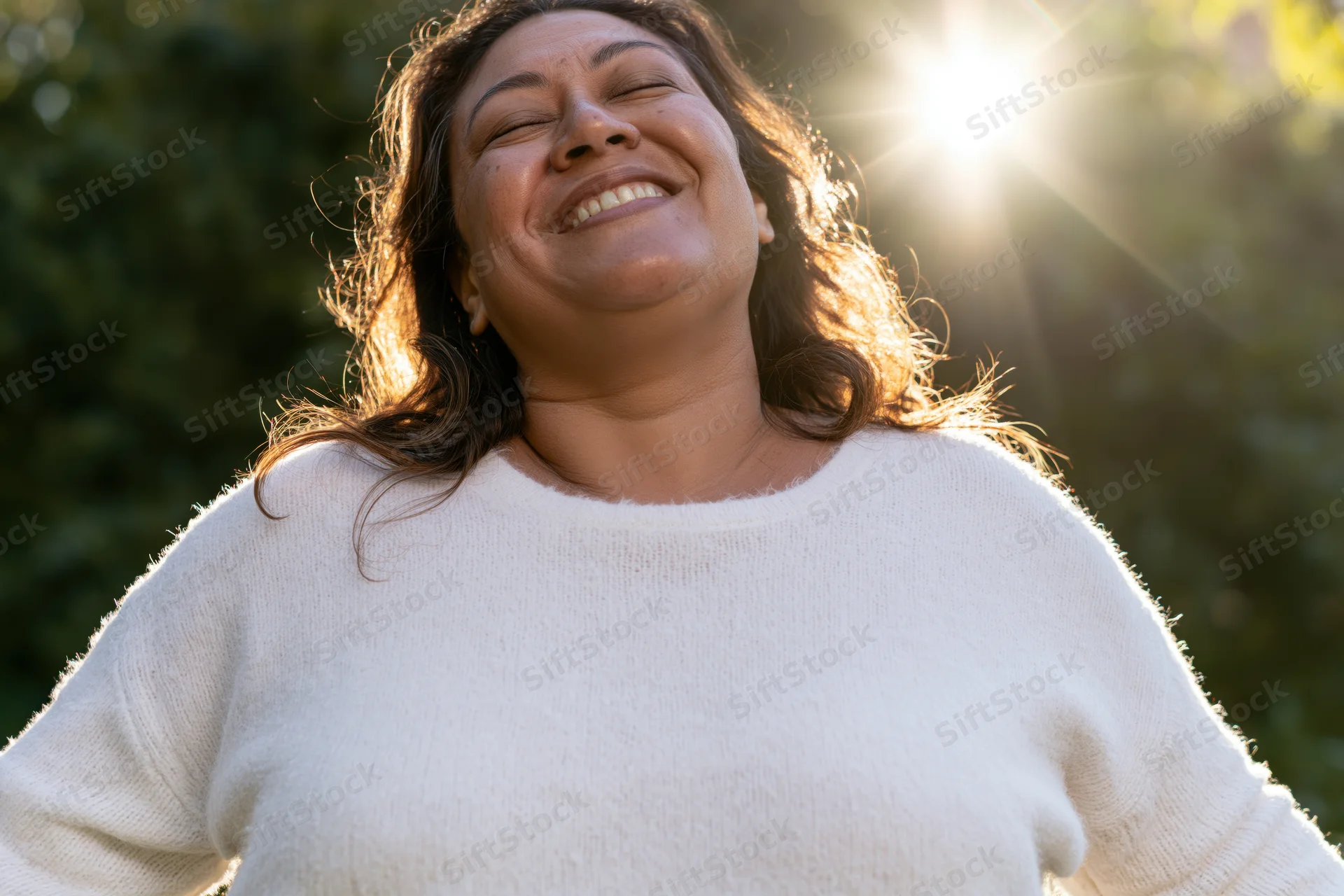 Woman smiling with eyes closed in sunlight outdoors